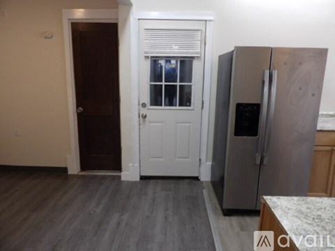 A kitchen with a refrigerator and a door leading to another room.