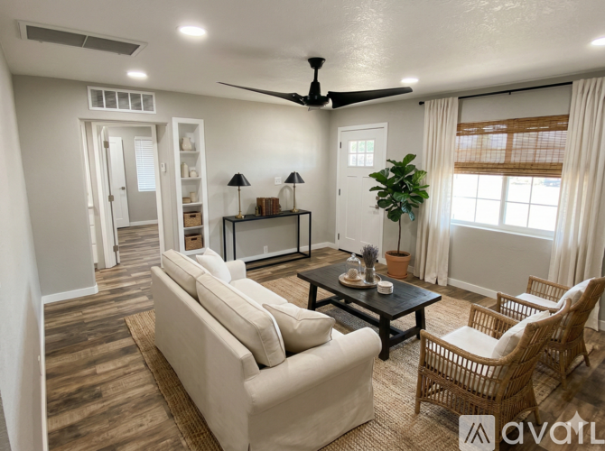 A living room with a beige couch, a black coffee table, and a ceiling fan.