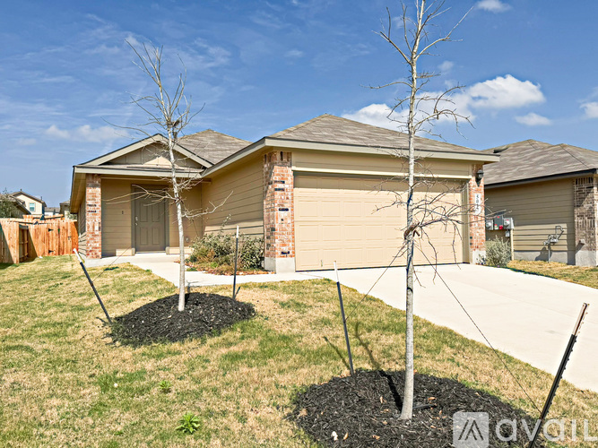 A beige house with a brown roof and a white garage door.