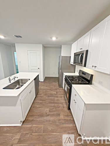 A kitchen with white cabinets and a wooden floor.