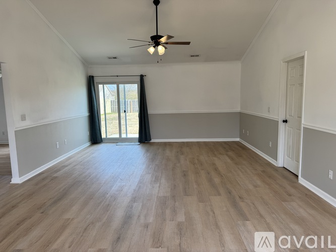 A spacious room with a ceiling fan and wooden flooring.