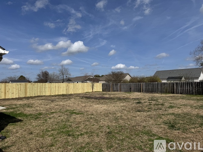 A backyard with a wooden fence and a grassy field.