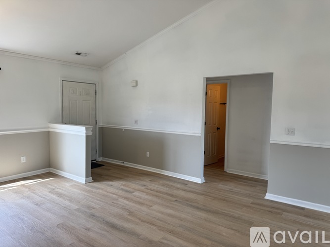 A room with a wooden floor and a door on the right side.