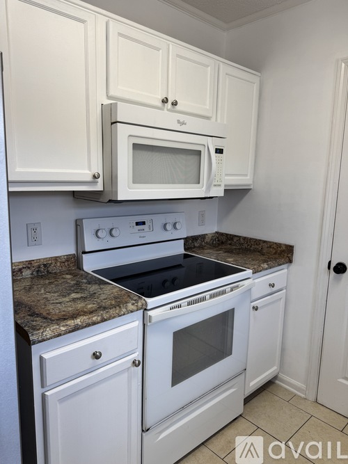 A kitchen with white cabinets and a granite countertop.