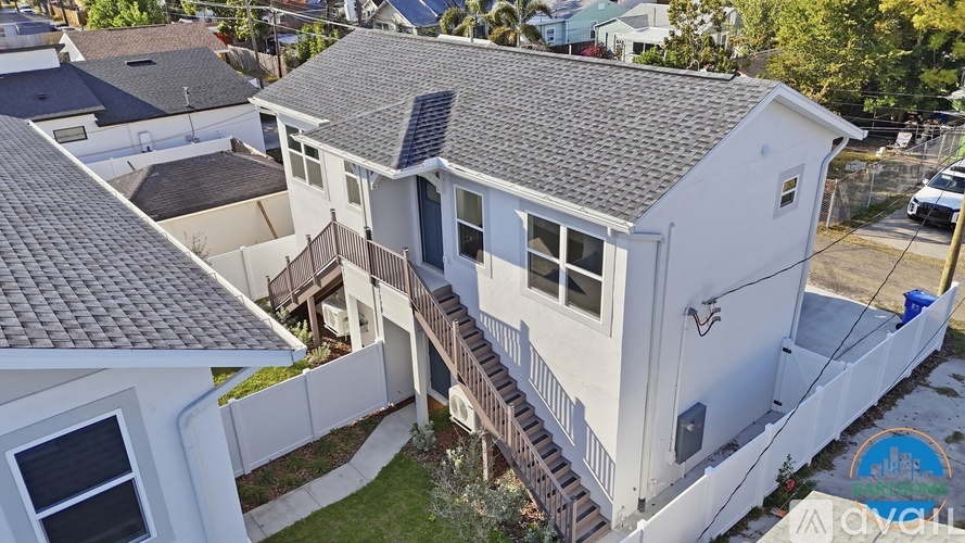 A white house with a grey roof and a balcony.