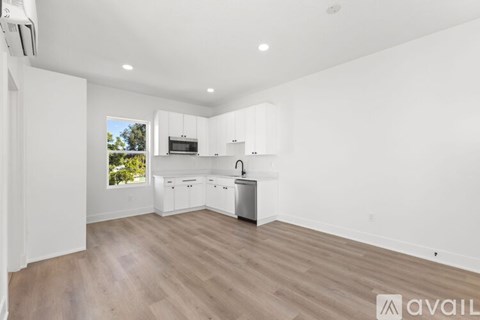 A spacious kitchen with white cabinets and a wooden floor.