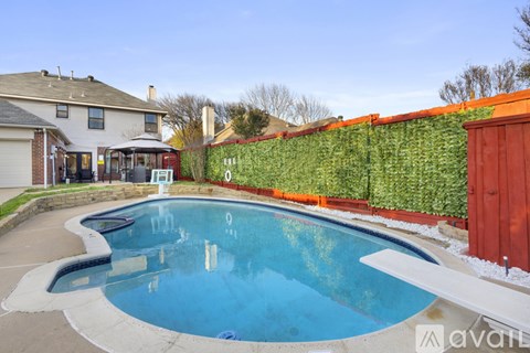 A swimming pool in a backyard with a house and a wall of green plants.