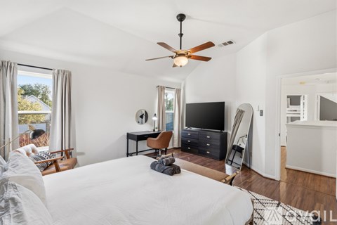 A bedroom with a large bed and a ceiling fan.