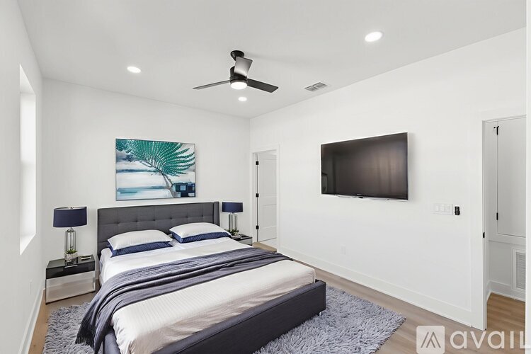 A bedroom with a large bed and a flat screen TV mounted on the wall.