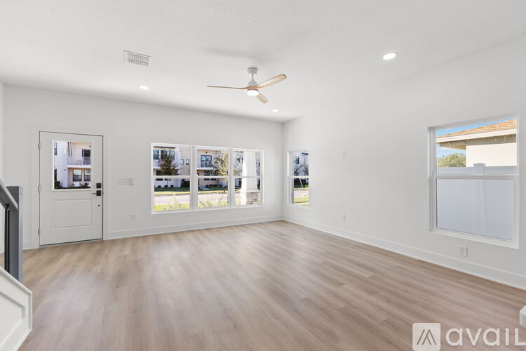 A spacious room with a ceiling fan and a view of the outdoors through the windows.