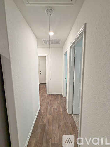A long hallway with wood floors and white walls.