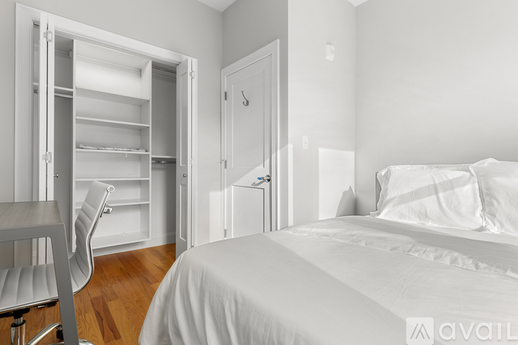 A white bedroom with a bed, chair, and open closet.