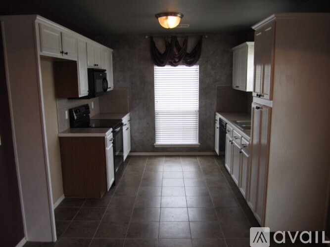 A kitchen with brown cabinets and a black microwave.