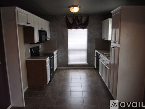 A kitchen with brown cabinets and a black microwave.
