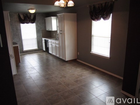 A kitchen with white appliances and brown tile flooring.
