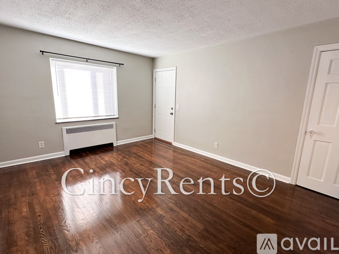 A room with wooden floors and a window with blinds.