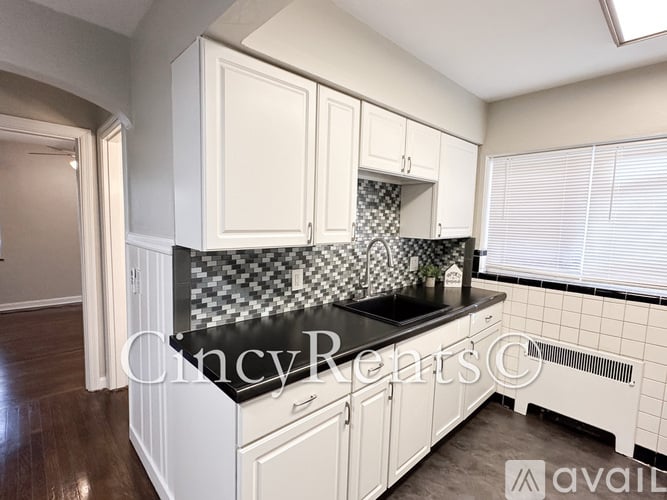 A kitchen with white cabinets and a black countertop.