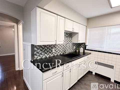 A kitchen with white cabinets and a black countertop.