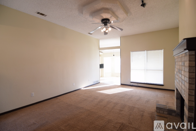 A spacious room with a ceiling fan and a fireplace.