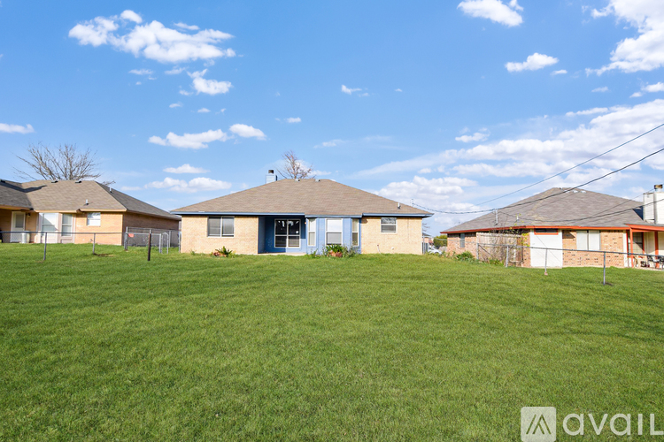 A grassy field with a house and a fence in the background.