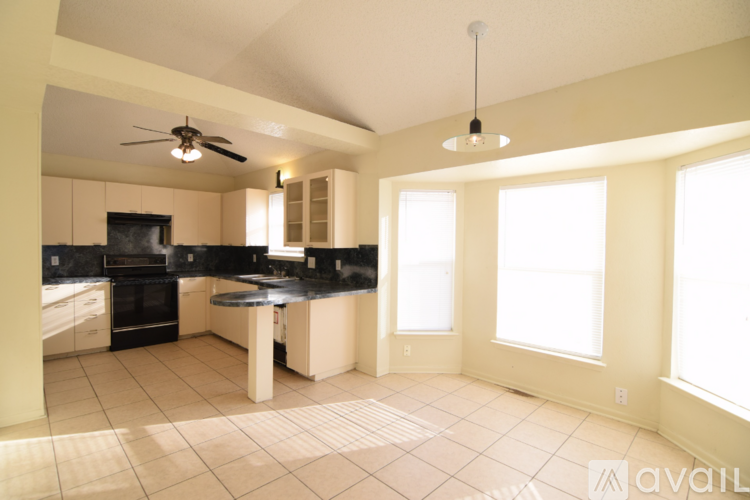 A kitchen with a black countertop and a ceiling fan.