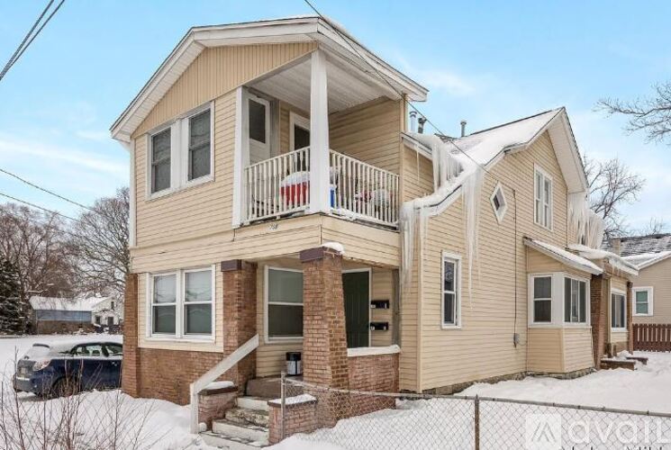 A two-story house with a balcony and a car parked in the driveway.