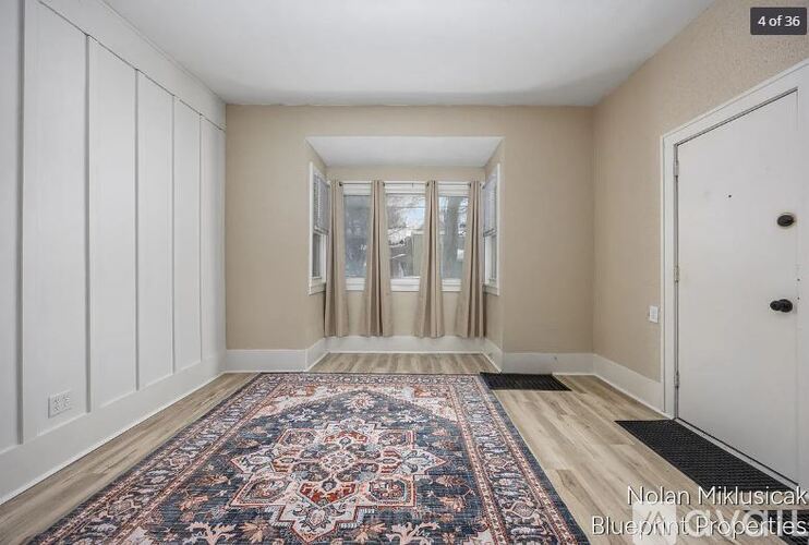 A room with a rug on the floor and a door on the right.