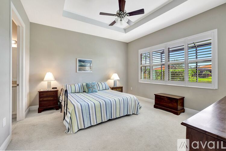 A bedroom with a bed, two lamps, and a ceiling fan.