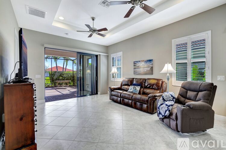 A living room with a brown leather couch and a ceiling fan.