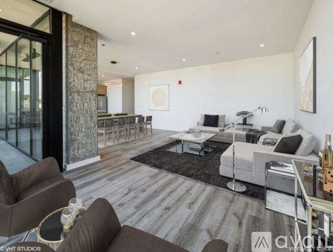 A spacious room with wooden flooring and large windows.