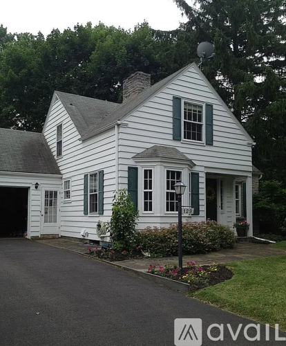 A white house with green shutters and a black roof.