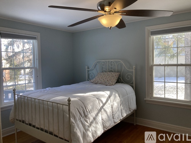 A bedroom with a white bed and a ceiling fan.