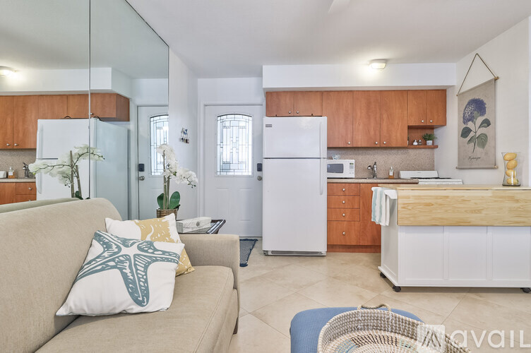 A kitchen with a white refrigerator and a beige couch with a blue and white pillow.