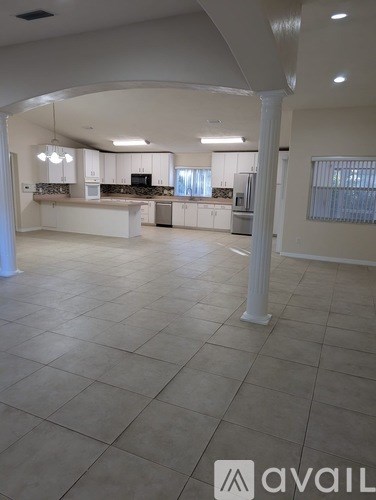 A spacious kitchen and living room with white cabinets and a tiled floor.
