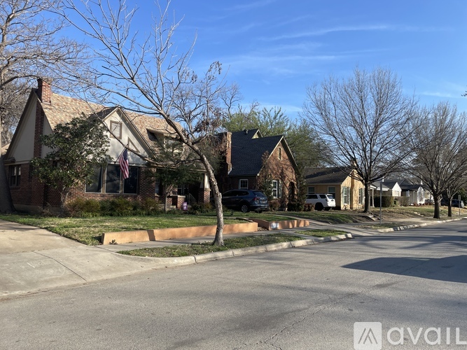 A street view of a residential area with houses and trees.