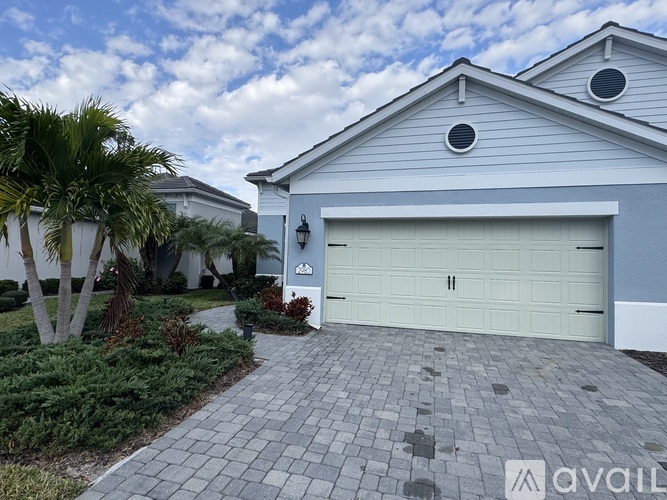 A house with a white garage door and a driveway made of grey bricks.