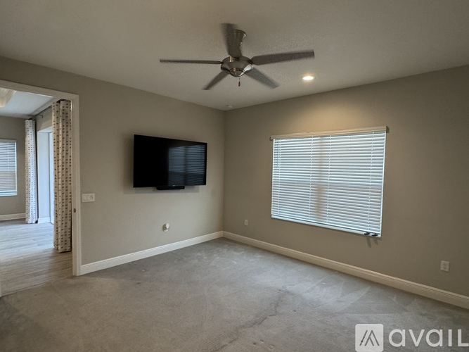 A spacious room with a ceiling fan and a flat screen TV mounted on the wall.