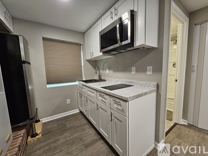A kitchen with white cabinets and a black refrigerator.