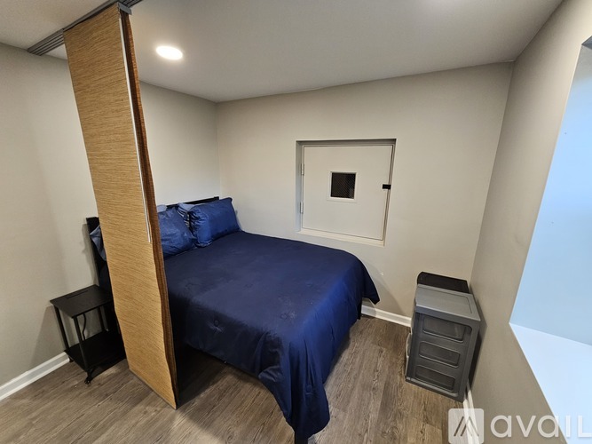 A bedroom with a bed, nightstand, and a small window.