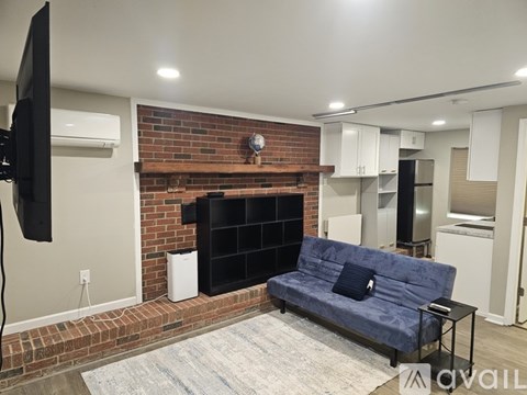 A living room with a blue couch and a brick fireplace.