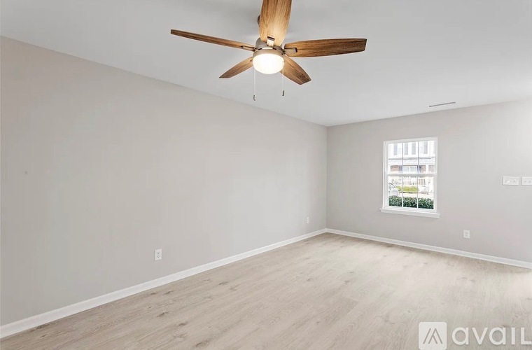 A room with a ceiling fan and a window showing a view of a building outside.