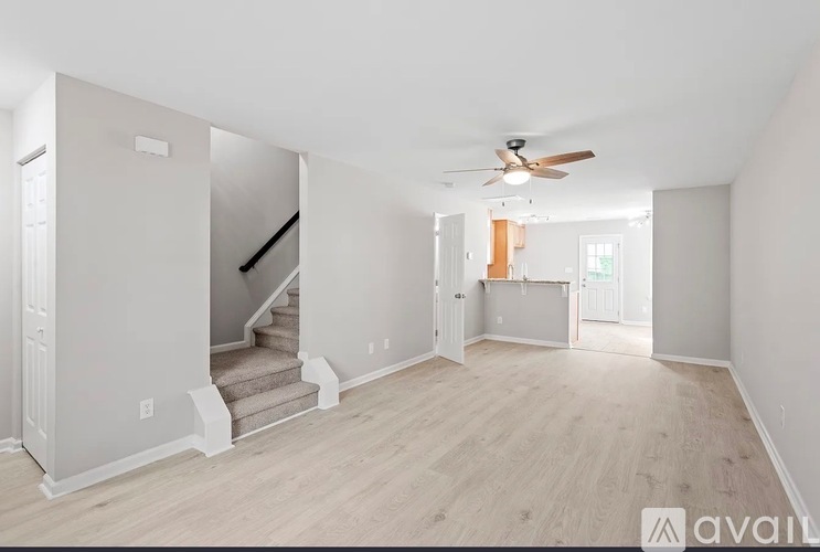 A spacious room with a staircase and a ceiling fan.
