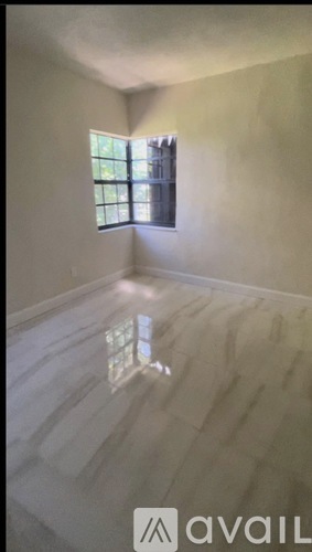 A room with a window and a reflection on the floor.