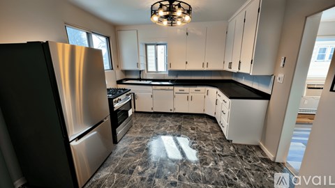 A kitchen with a marble floor and a refrigerator on the left.