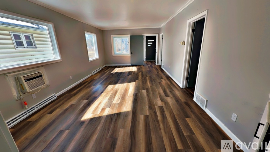 A room with wooden flooring and a window on the left side.