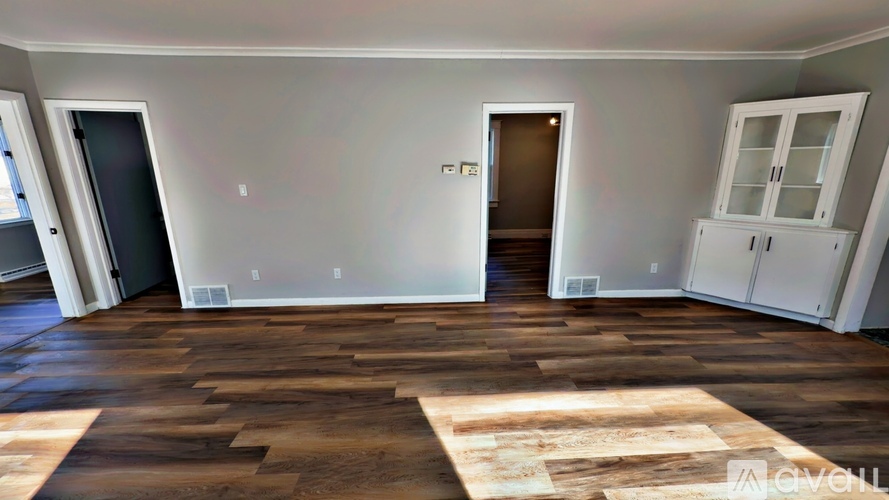 A room with wooden flooring and white walls.