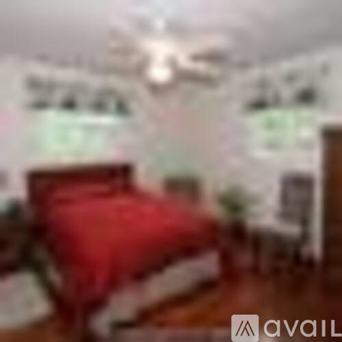 A bedroom with a red bedspread and a wooden bed frame.
