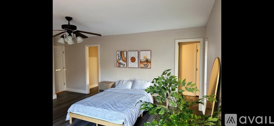 A bedroom with a bed, a ceiling fan, and a plant.