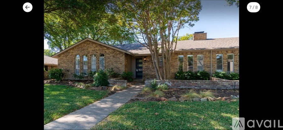 A house with a stone facade and a large tree in front.