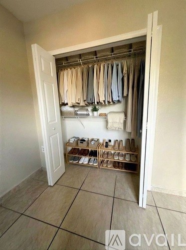 A room with a closet full of clothes and shoes.